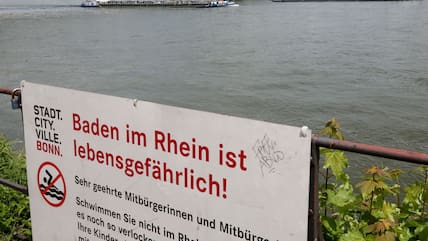 Mit einem Hinweisschild "Baden im Rhein ist lebensgefährlich" warnt die Stadt Bonn die Menschen vor den Gefahren beim Schwimmen im Rhein.