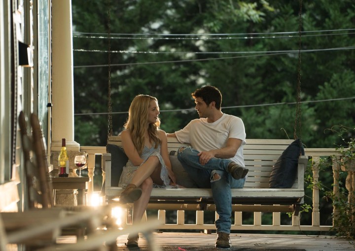 A young woman and man sit besides each other on a porch.