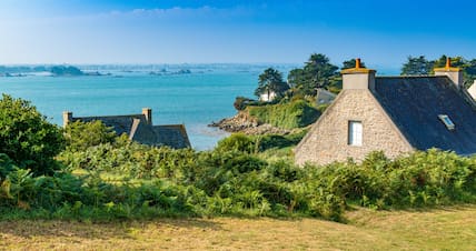 Historische Häuser auf der  Île de Batz mit türkisblauem Meer im Hintergrund.