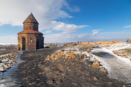 Kleine Steinkirche in Kars in einer steinigen Landschaft, die teils noch Schnee bedeckt