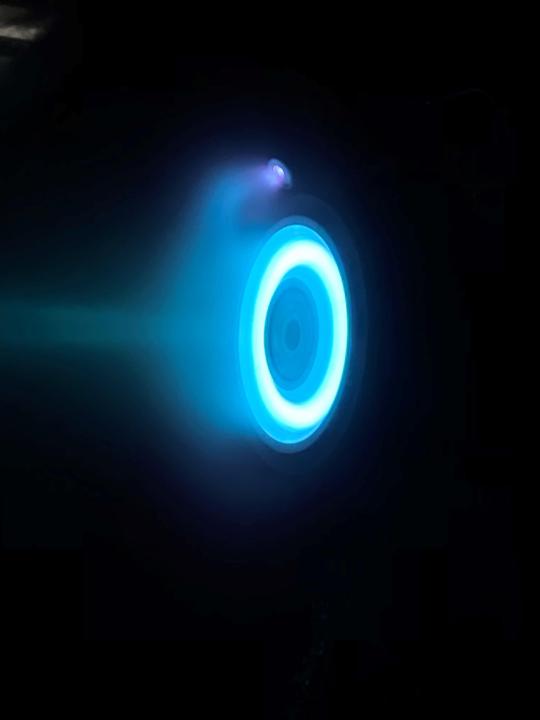 This photo captures an operating electric thruster identical to those being used to propel NASA’s Psyche spacecraft. The blue glow comes from the charged atoms, or ions, of xenon.