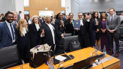 Payam Akhavan (M), Anwalt aus dem Iran und Vorsitzender der Kommission der kleinen Inselstaaten für Klimawandel und Völkerrecht, macht das Victory-Zeichen und hält das Rechtsgutachten des Internationalen Seegerichtshofs in der Hand.