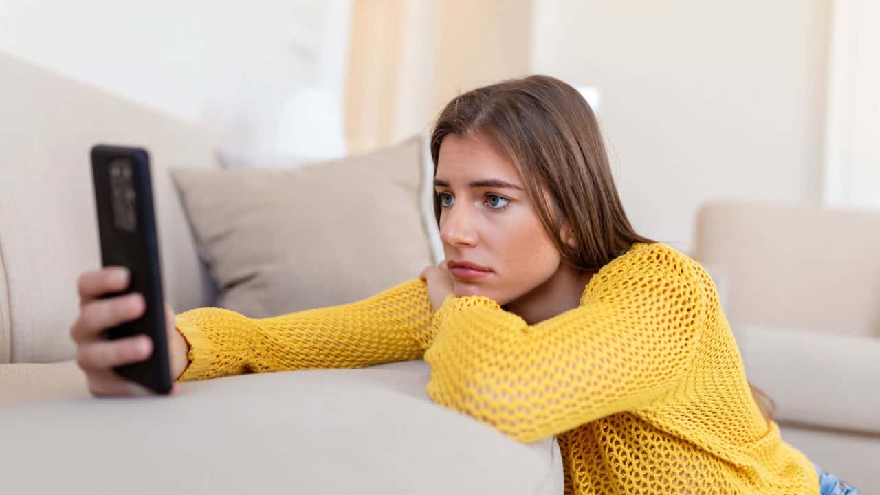 sad young woman holding smartphone