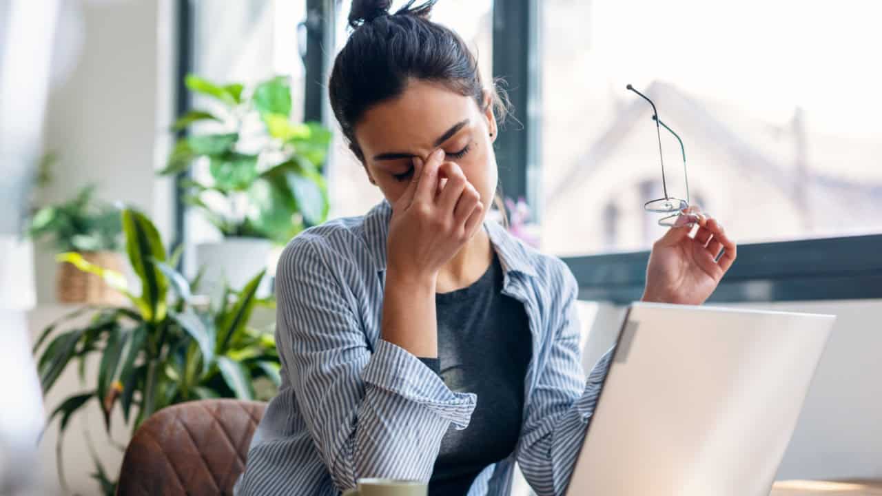 woman working from home on laptop looking worried, tired and overwhelmed