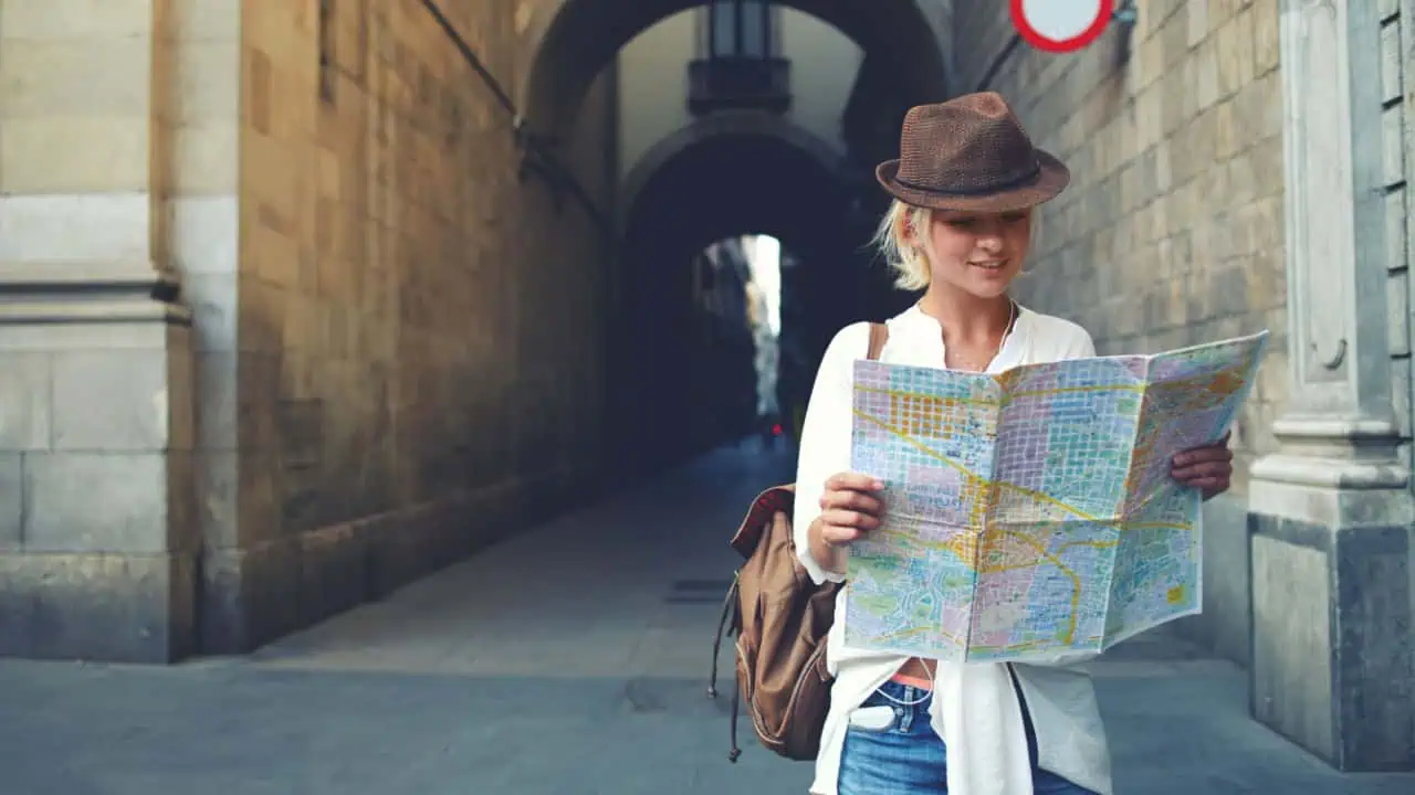 female tourist with backpack on shoulders exploring map