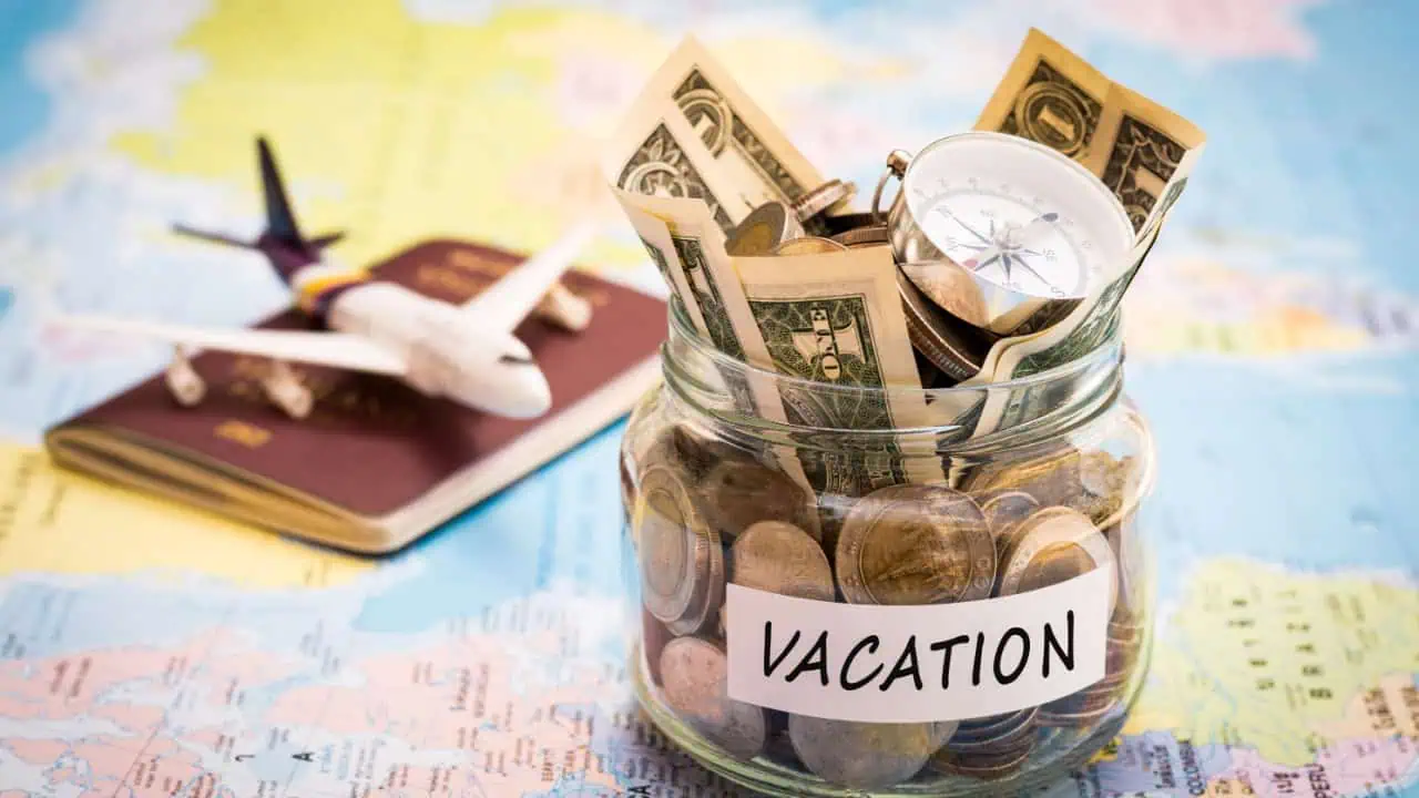 Vacation money savings in a glass jar with compass