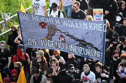 Teilnehmer der „Revolutionären 1. Mai-Demonstration" halten ein Banner mit dem Schriftzug „Die Reichen wollen Krieg - Die Jugend eine Zukunft" hoch.