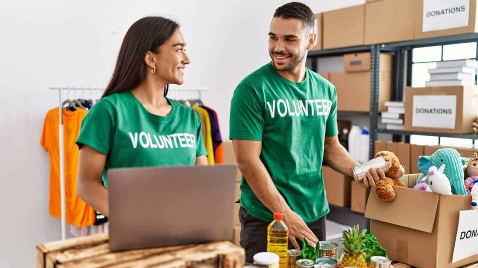 Young latin volunteer couple using laptop working at charity center.