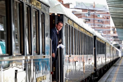 Luxuszug Venice Simplon-Orient-Express mit blauen Waggons, aus denen ein Schaffner schaut