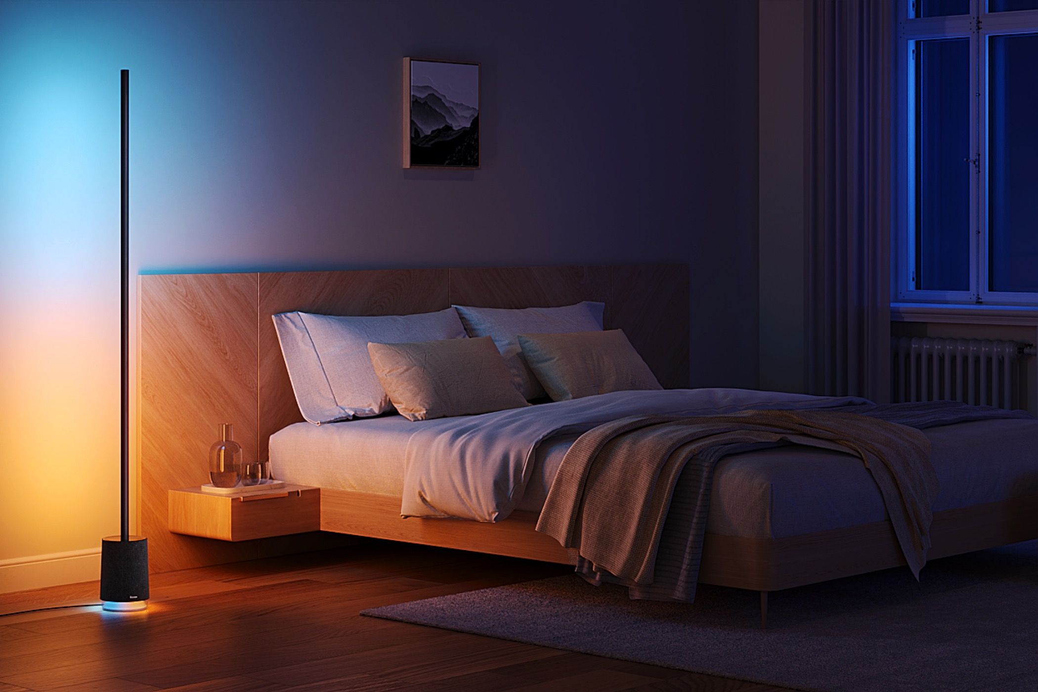 A colorful Govee Floor Lamp illuminating next to a bed.