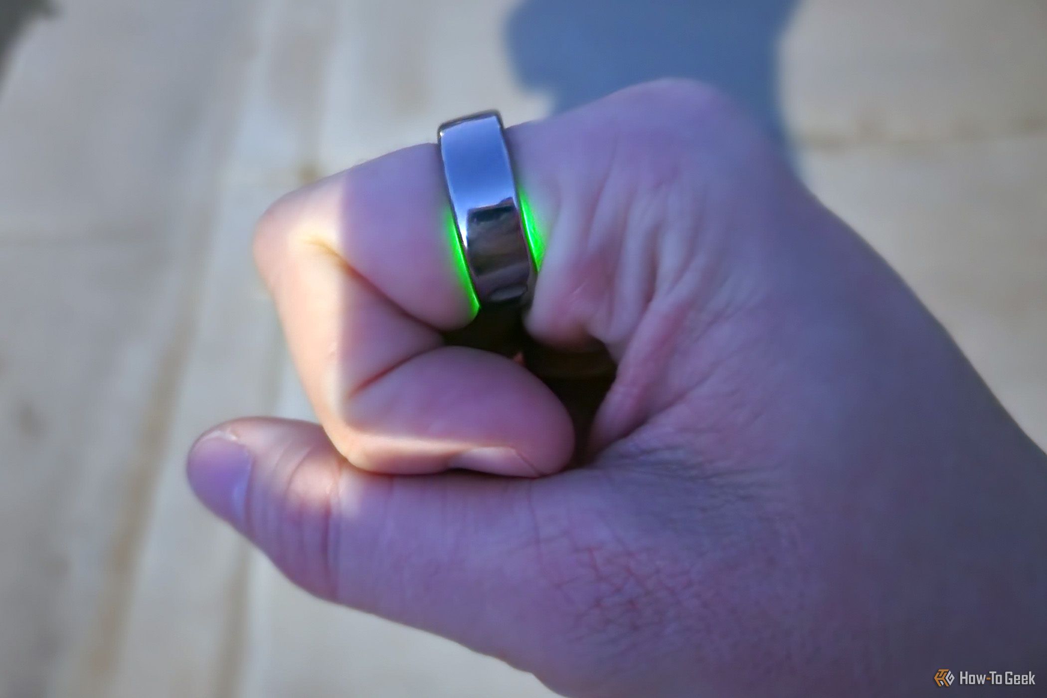 A person's fist showing the 3rd Generation Oura Ring's heart rate monitor light.