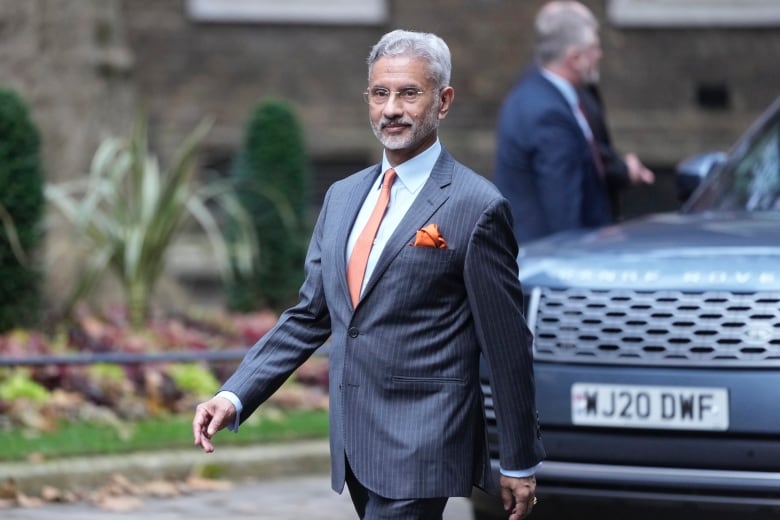 A man wearing a suit walks on the street.