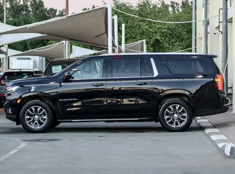 A black SUV is seen parked on grey pavement.