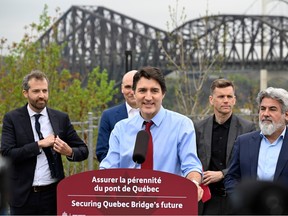 Men stand around a podium with a bridge in the background