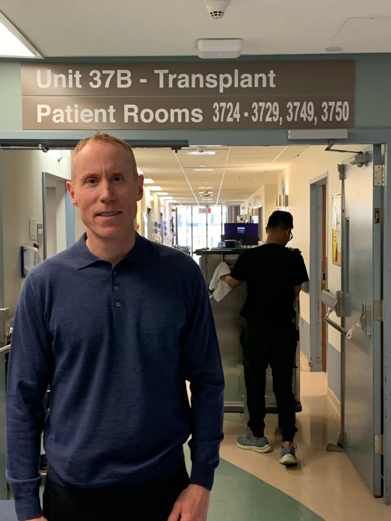 A man stands in front of a sign that says "transplant" in a hospital in Calgary.