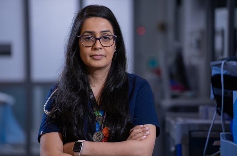 A female physician standing in scrubs with a stethoscope around the neck.