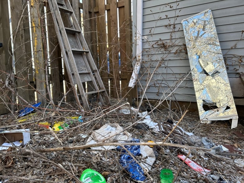 A broken mirror and piles of garbage in a yard.