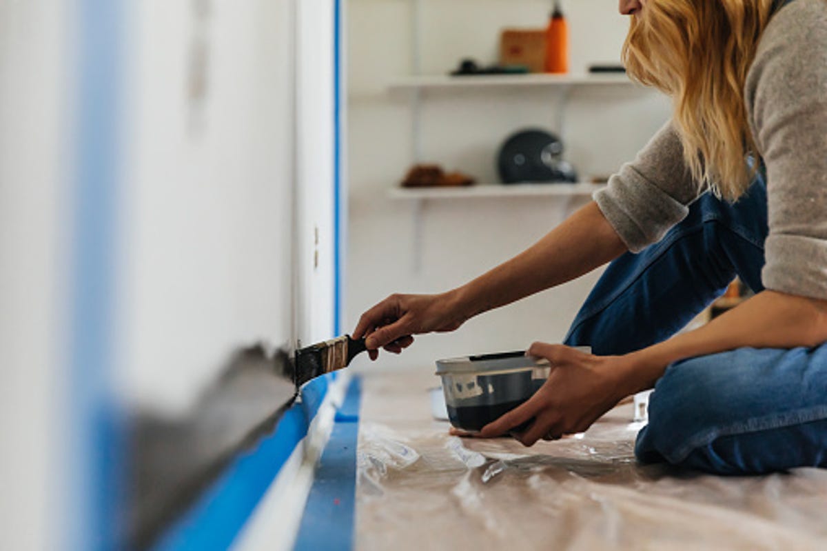 A women sitting on the floor painting a wall