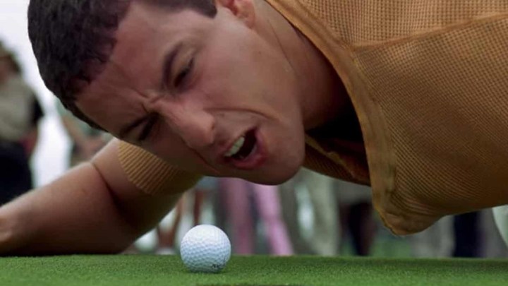 Adam Sandler on the ground screaming at a golf ball in a scene from Happy Gilmore.