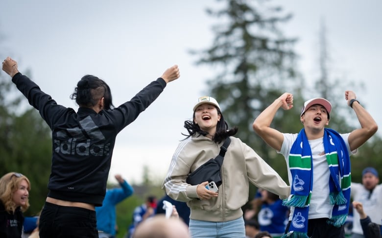 Three young people jump in the air, smiling.