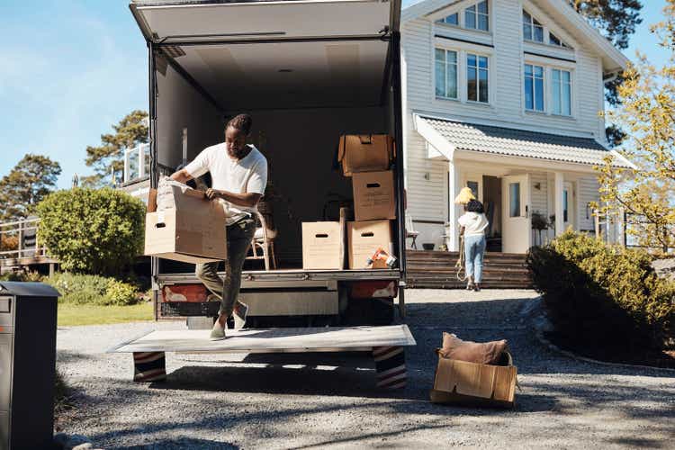 Full length of man unloading cardboard box from van