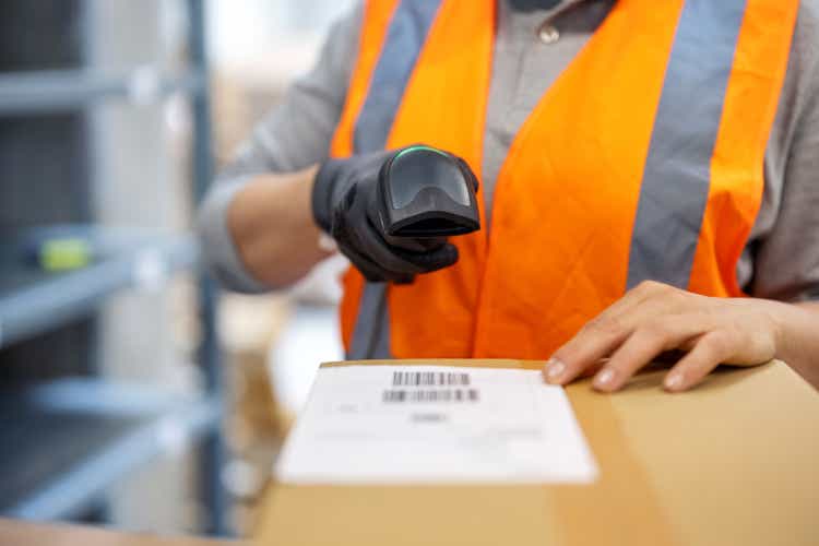 Close-up of a woman warehouse worker scanning package with bar code scanner