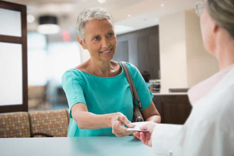 Woman passing insurance card in hospital