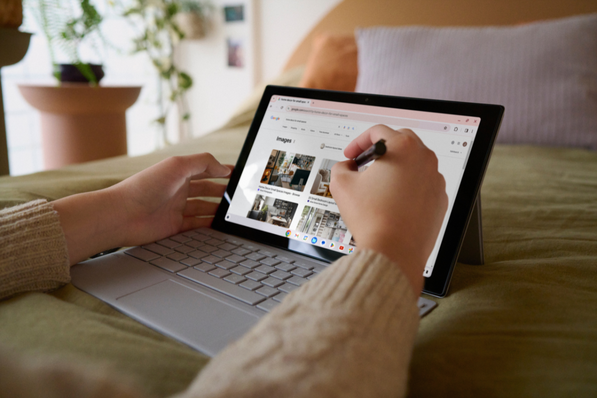 a close-up of a person touching a stylus to a Asus Chromebook CM30's screen in bed