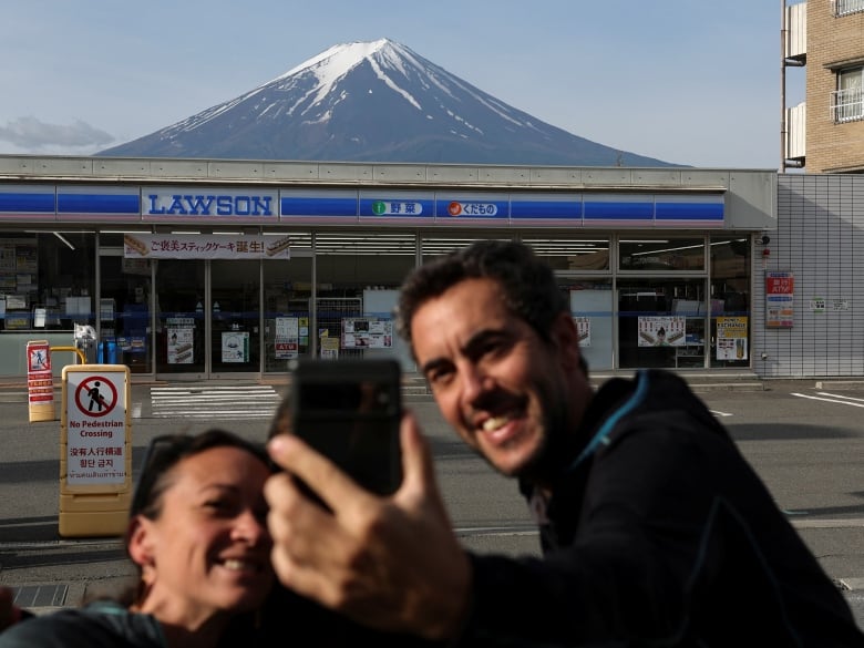 Tourists take photos of Mount Fuji in the background. 