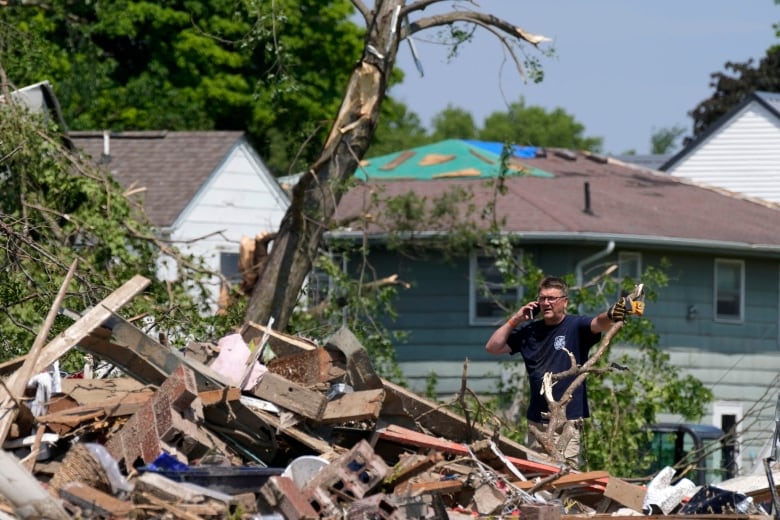 A man is seen talking on a cellphone in front of a tornado-damaged home in Greenfield, Iowa, on Wednesday, May 22, 2024.