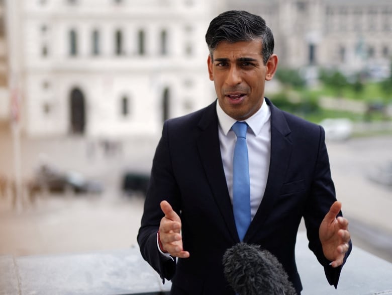 A man in a suit gestures at a microphone