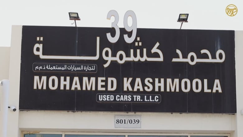 A black sign with the words "Mohamed Kashmoola Used Cars" in bold letters.