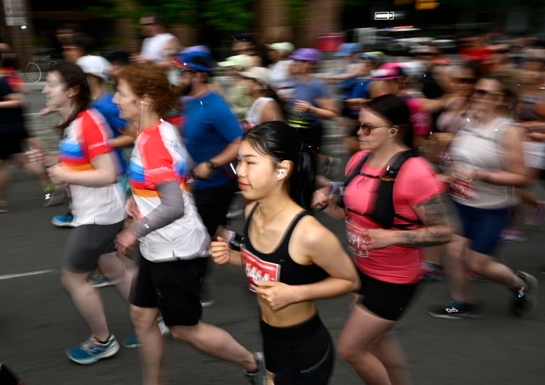 A group of people run down the street in race gear