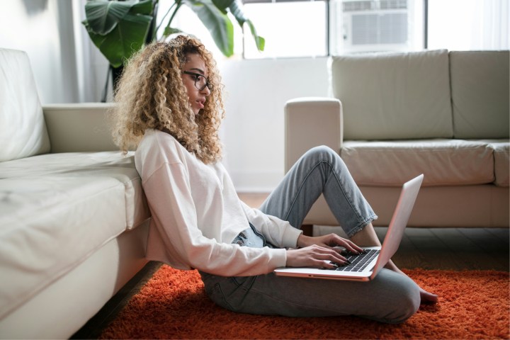 Woman using a laptop on the floor.