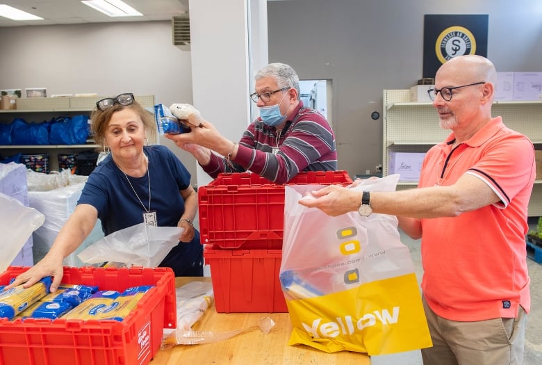 Volunteers place donated food items into bags at a Sun Youth location in Montreal, Monday, July 11, 2022.