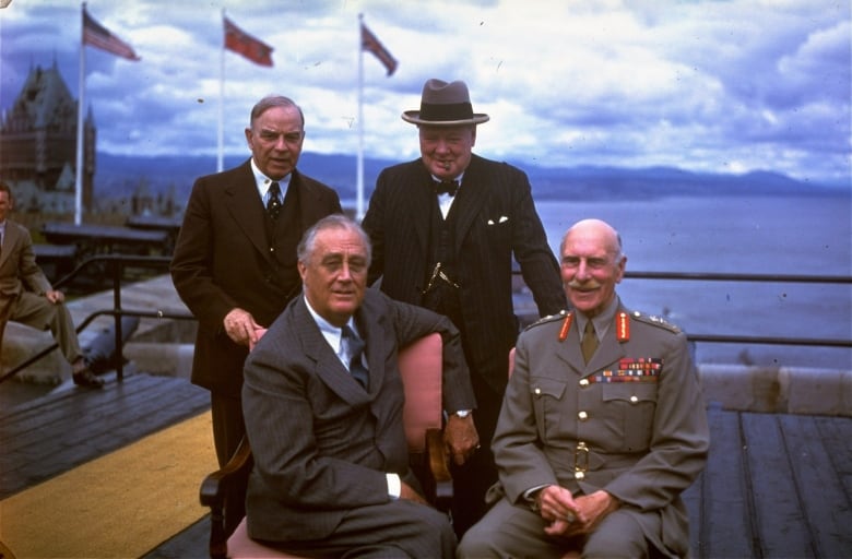 Three world leaders in suits and Canada's governor general in military regalia, seen in a colour photo on a cliff overlooking Quebec's Chateau Frontenac