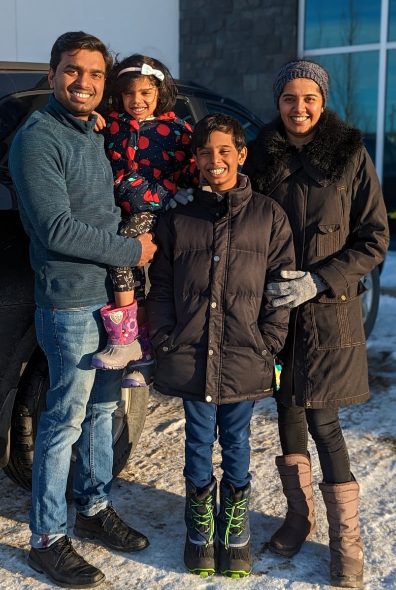 Sumesh Pulavathil and Gayathri Ramdas pose for a photo with their two children. 