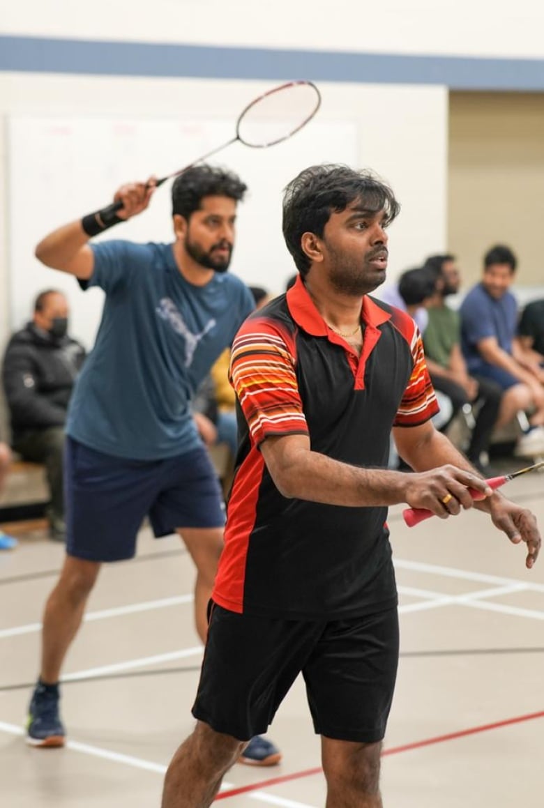 Two men play a game of badminton.