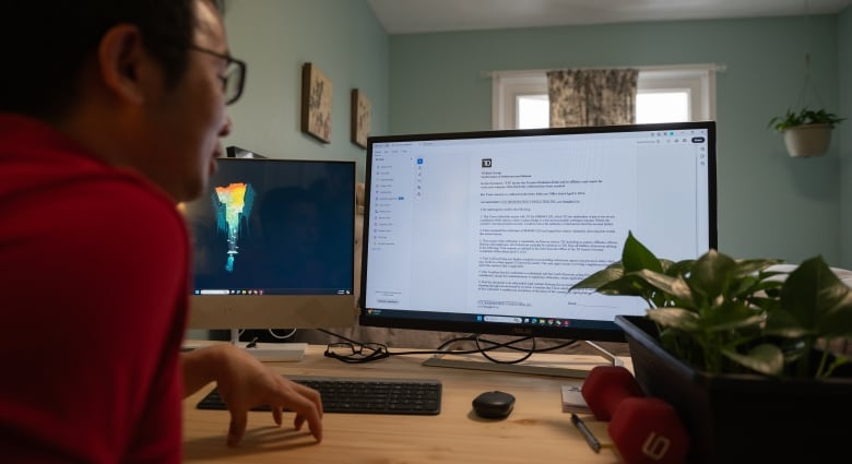 An East Asian man wearing a red shirt sits in front of his desktop computer. He's looking at an NDA on the screen that TD Bank emailed him. 