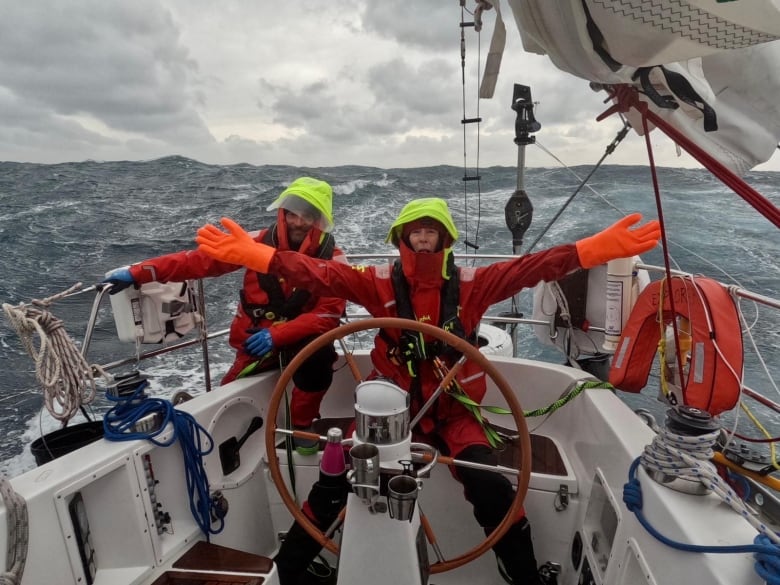 Two people at the helm of a sailboat 