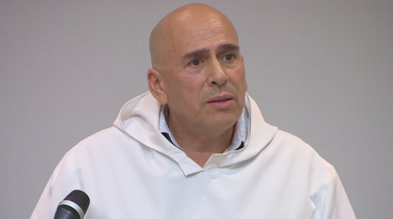 A bald man wearing a white hooded pullover.