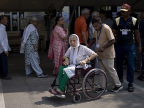 An elderly voter in a wheelchair shows her index finger marked with an indelible ink after she cast her vote in the sixth round of polling in India's national election in New Delhi, India, Saturday, May 25, 2024.