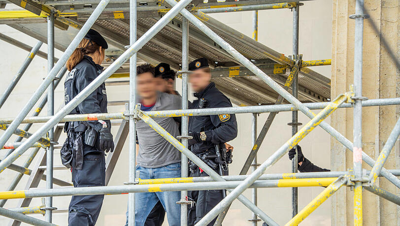 Als die beiden Identitären herunterklettern, nimmt sie die Polizei fest. Kurz vorher segelte das Banner herab.