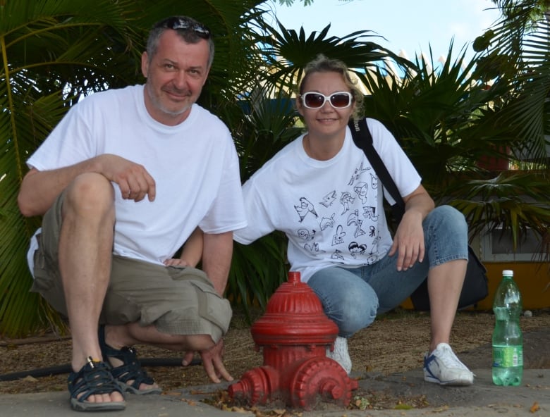 Andrew and Anna Dyczkowski on vacation, posing in front of palm trees. 