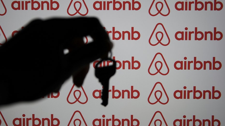 Airbnb logo with the shadow of a hand holding a house key