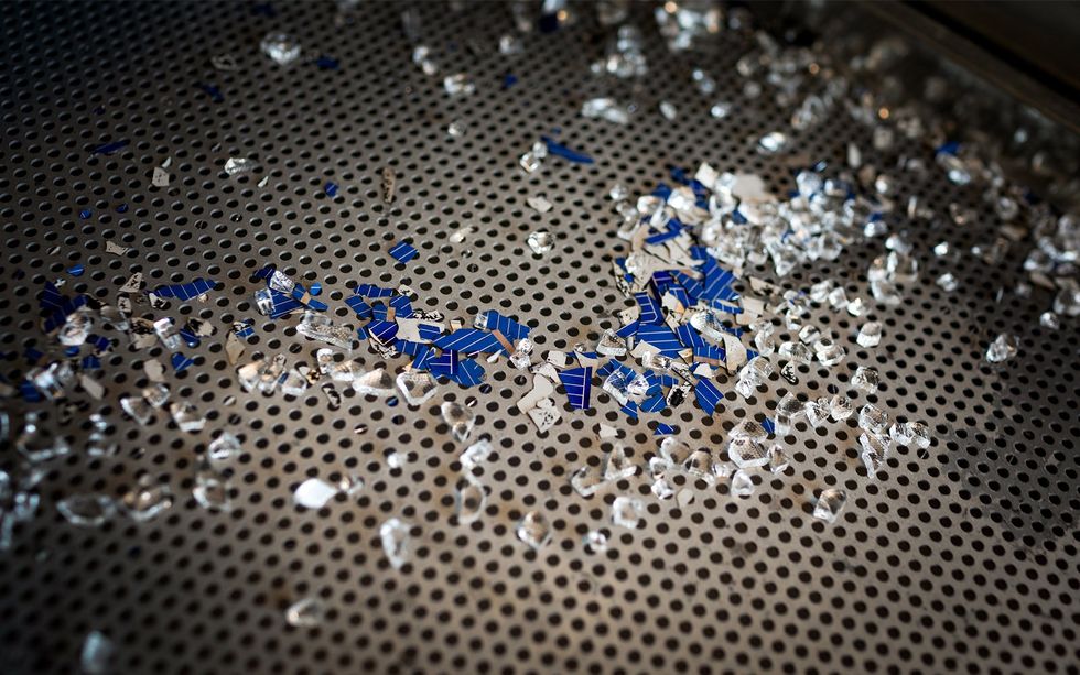 Broken pieces of clear glass and blue silicon on a perforated metal tray