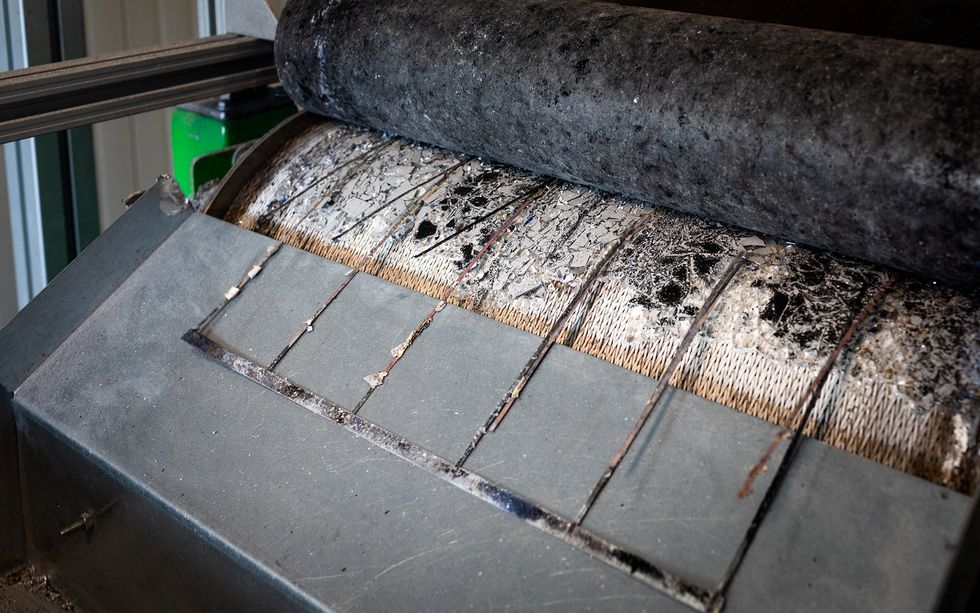 Thin pieces of copper emerge from a metal roller