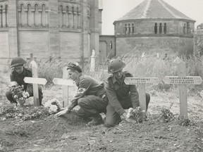 D-Day on June 6, 1944 was a big success, but the Germans dug in and the ensuing Battle of Normandy raged 'til August. Here British and Canadian troops are being buried side by side with French civilians in a Normandy cemetery. The soldiers placing flowers on the graves are Pte. W. Yoing of Sydney, N.S., Pte. H. Roach of Ottawa, and Pte. M.G. Newberry of Victoria, B.C.