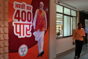 A supporter of the Bharatiya Janata Party (BJP) walks past a poster of Prime Minister Narendra Modi at its party's state headquarters in Gandhinagar, India, June 4, 2024. The poster reads, 