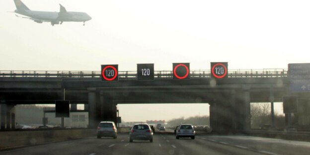 Blick auf eine Autobahn mit einem Flugzeug im Landeanflug.